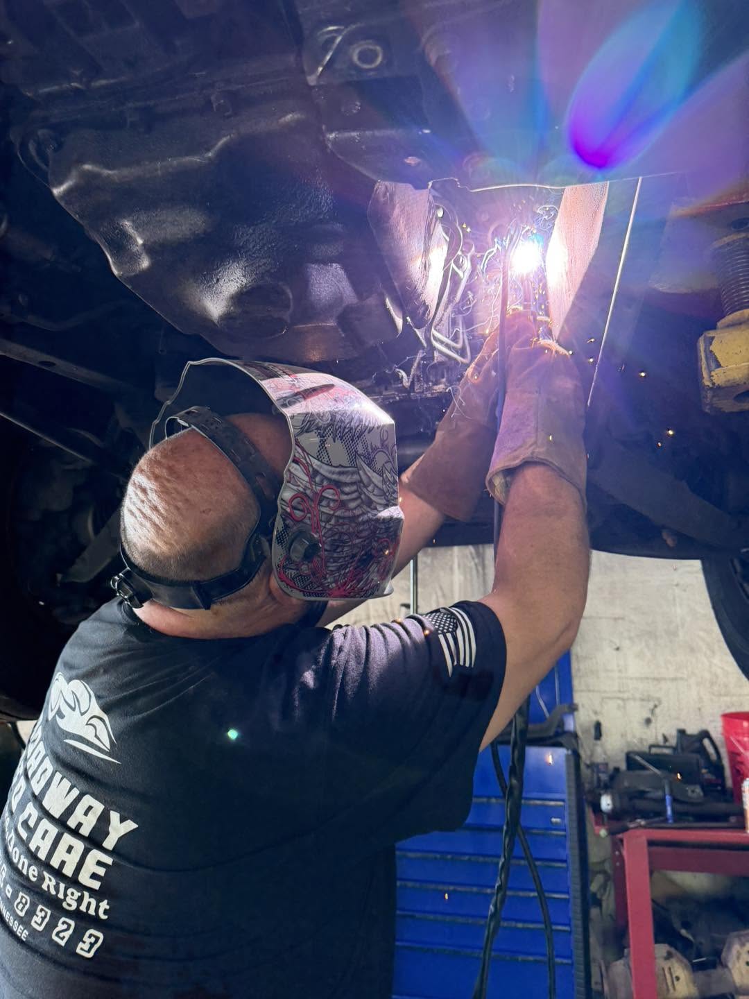 A Broadway Auto Care technician welding beneath a vehicle